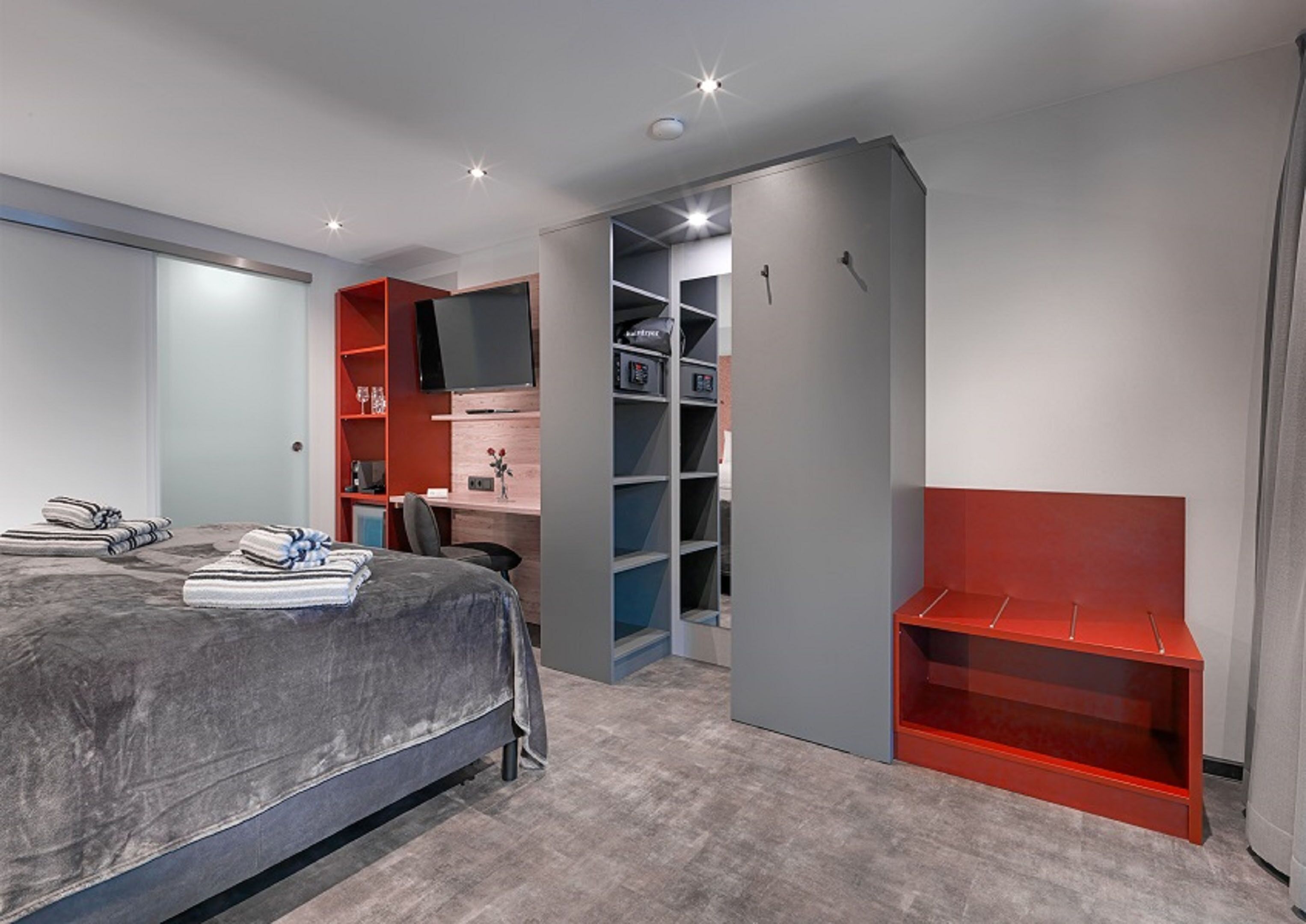 Quarto com cama, escrivaninha, cadeira e estantes embutidas.