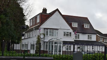 A two-story house with a white facade, a red brick chimney, and a conservatory.