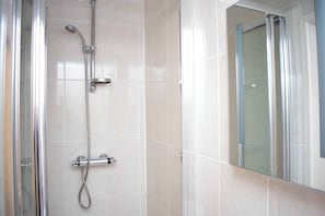 A shower with a glass door, a handheld showerhead, and a wall-mounted faucet. - Royal Square Hotel - NEC and Birmingham Airport (Birmingham)