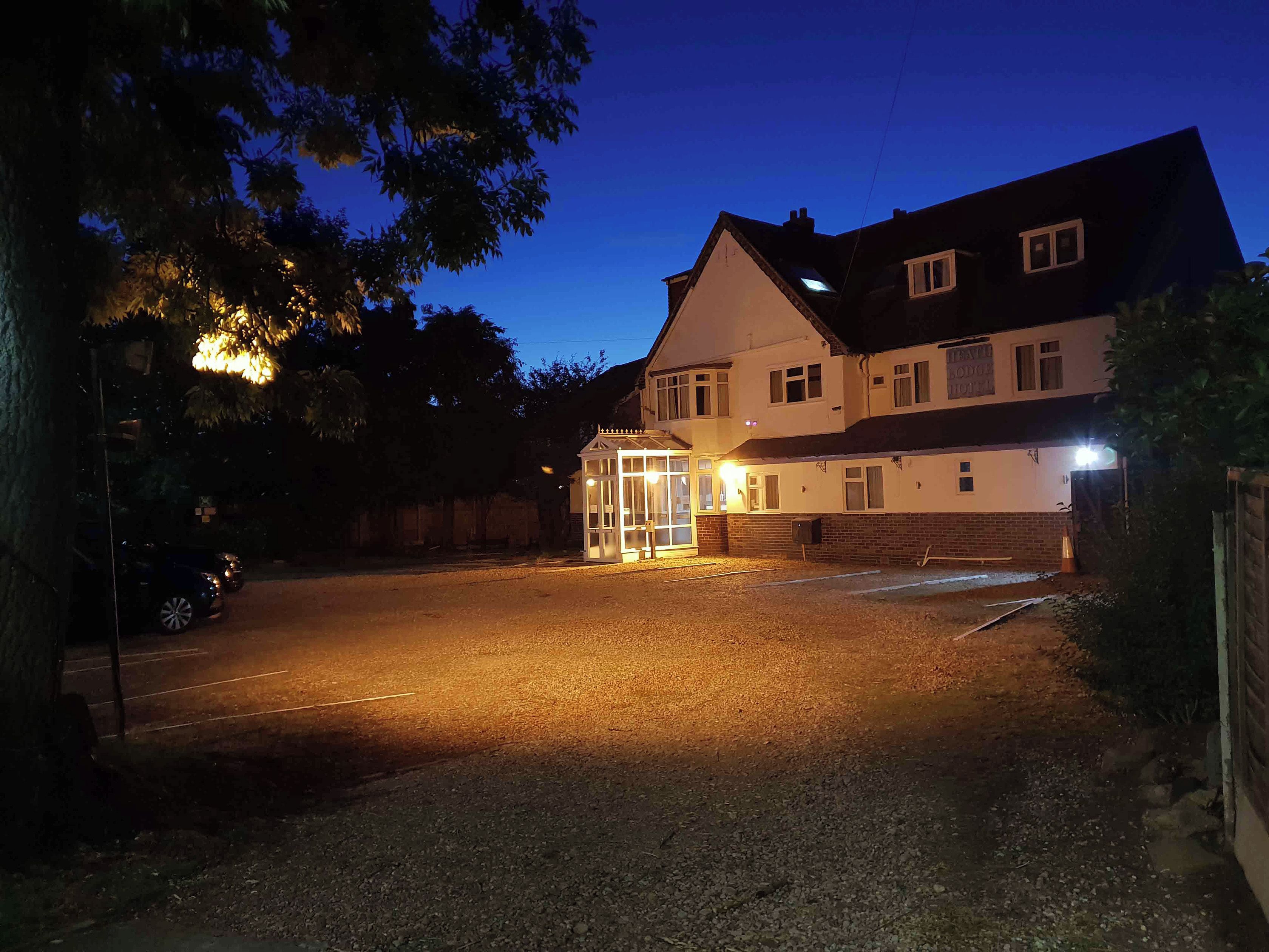 A two-story building with a gated entrance, a driveway, and a parking area.