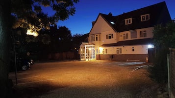 A two-story building with a gated entrance, a driveway, and a parking area.