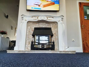 A fireplace with a modern design, a television mounted above it, and a door to the right. - Royal Square Hotel - NEC and Birmingham Airport (Birmingham)