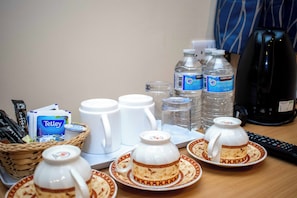 Una mesa con sobres de café, un hervidor, botellas de agua y sets de té.