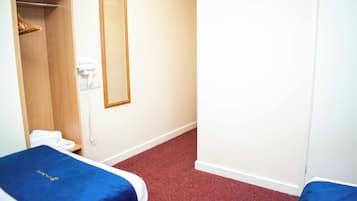A hotel room with two beds, a closet, a mirror, and a telephone.