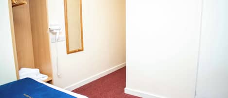 A hotel room with two beds, a closet, a mirror, and a telephone.