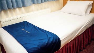 A bed with a white headboard, a blue blanket, and a red skirt.