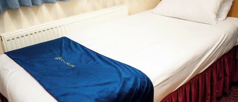 A bed with a white headboard, a blue blanket, and a red skirt.