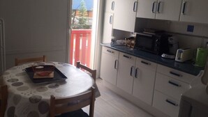 Een kleine keuken met een eettafel, stoelen en eenvoudige apparaten.