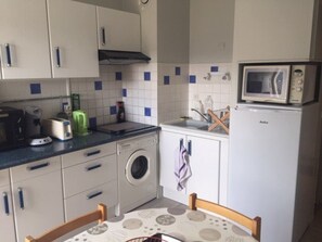 A compact kitchen with a washing machine, a microwave, and basic appliances. - Cozy studio 4 ppl, elevator, near slopes (Arette)