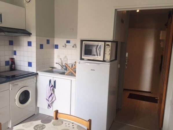 A compact kitchen with a washing machine, a microwave, and a sink.