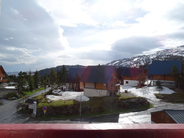 A rural mountain village with traditional wooden houses, a road with a no parking sign, and snow-covered hills in the background. - Cozy studio 4 ppl, elevator, near slopes (Arette)