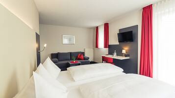 Une chambre d’hôtel avec un lit, un canapé, un bureau, une télévision et une fenêtre avec des rideaux.