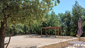 Un espace patio agrémenté d’un mur en pierre, d’une pergola en bois et de mobilier d’extérieur en métal.
