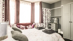 A bedroom with a bed, a desk, a wardrobe, and a window with curtains. - Sanderling (Scarborough)