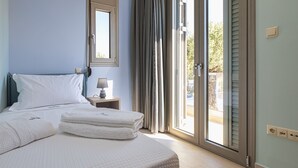 A hotel room with a bed, a nightstand, a lamp, and a view through a sliding glass door. - Cypress Village - Lux villa 5' from beach (Δαράτσος)
