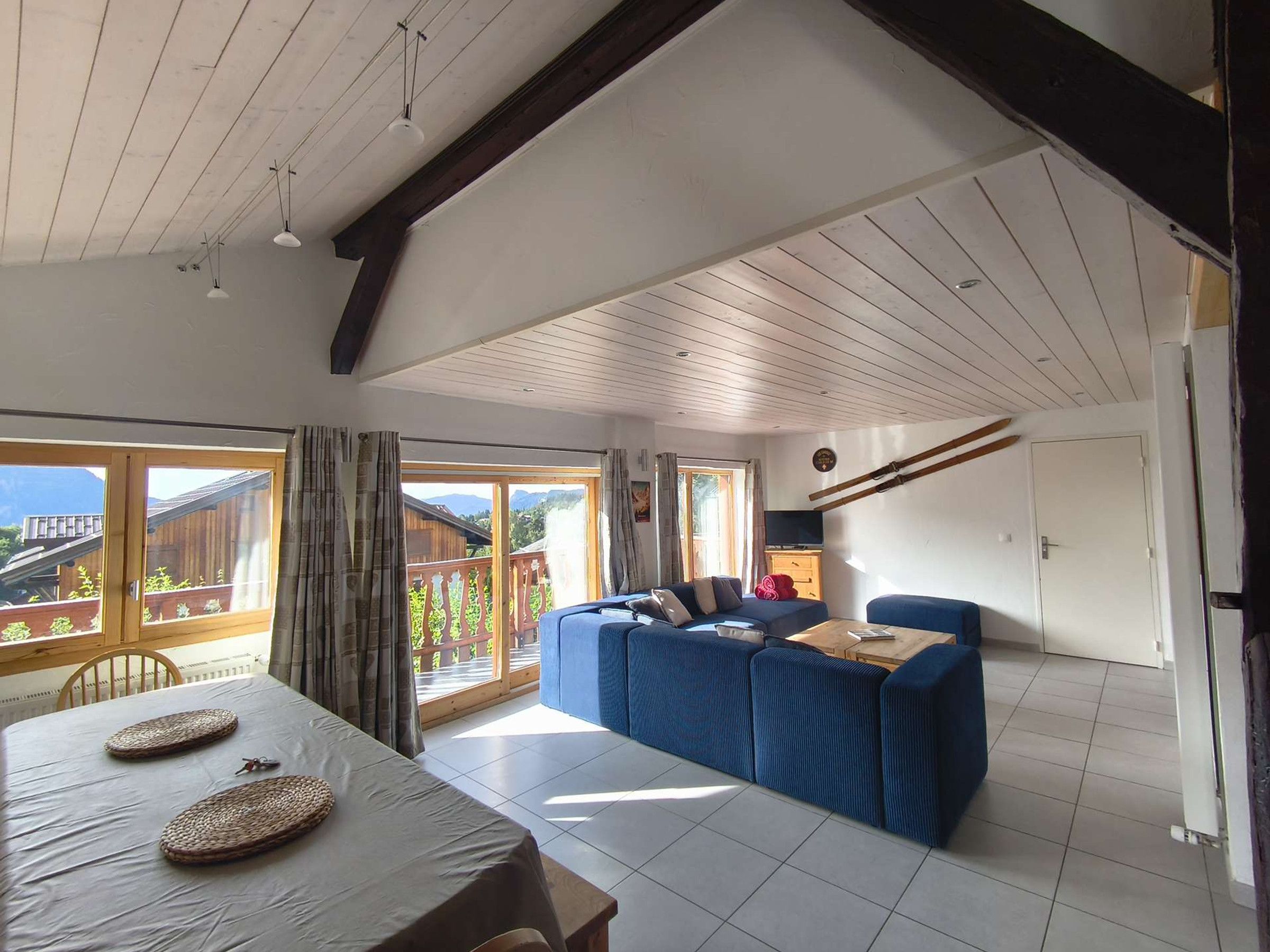 A room with a dining table, a sofa, and a television.