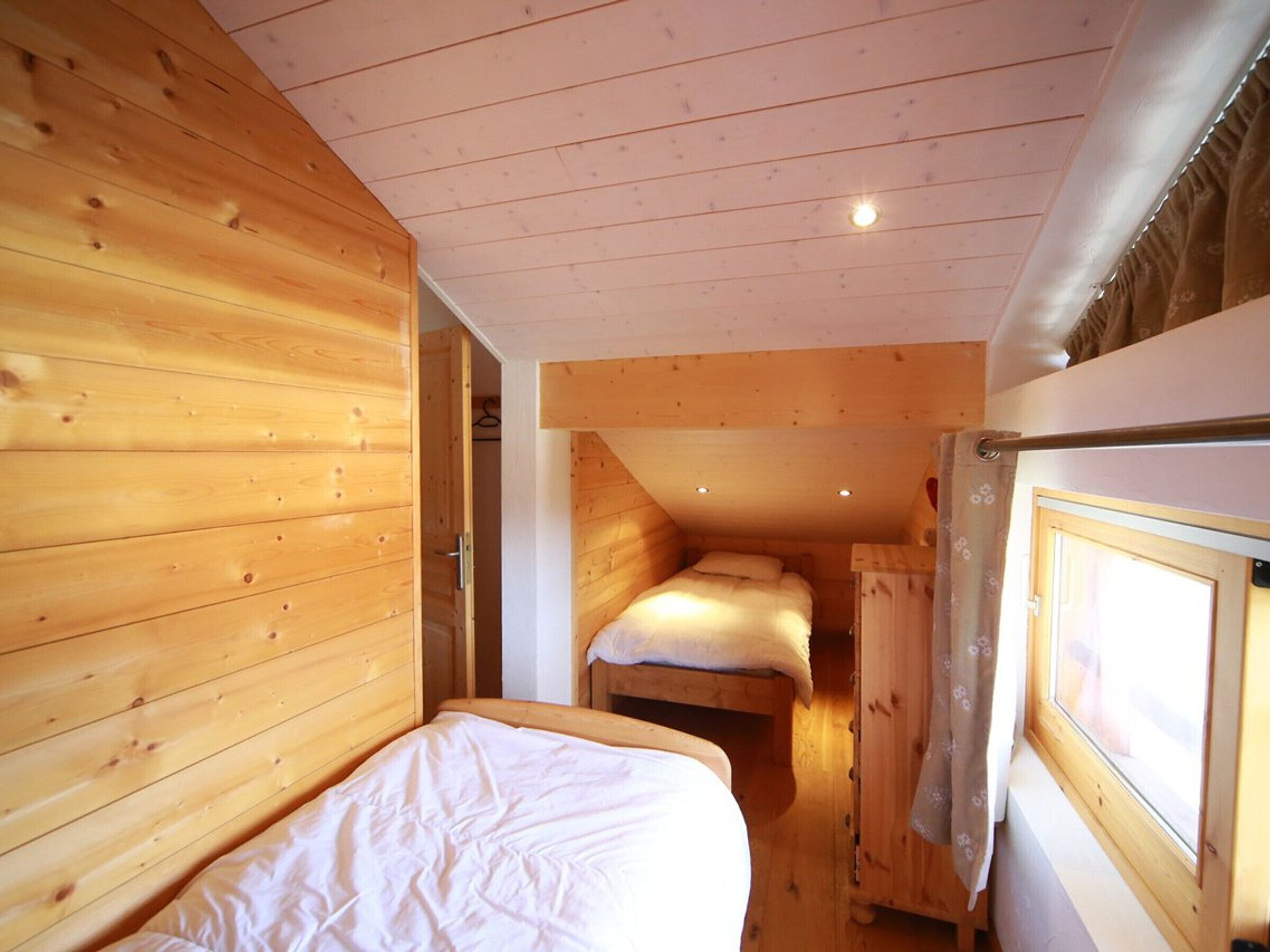 A wooden cabin room with a bunk bed and a single bed.