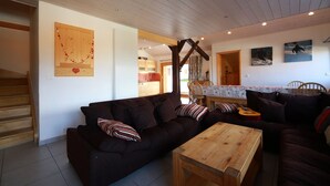 Una sala de estar acogedora con un sofá de color oscuro, una mesa de centro de madera y un comedor con una mesa y sillas.