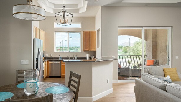 A modern kitchen with a central island, wooden cabinets, and a dining area with a table and chairs. - Walk to TPC | Pinnacle Peak Views | Gated Retreat (Scottsdale)