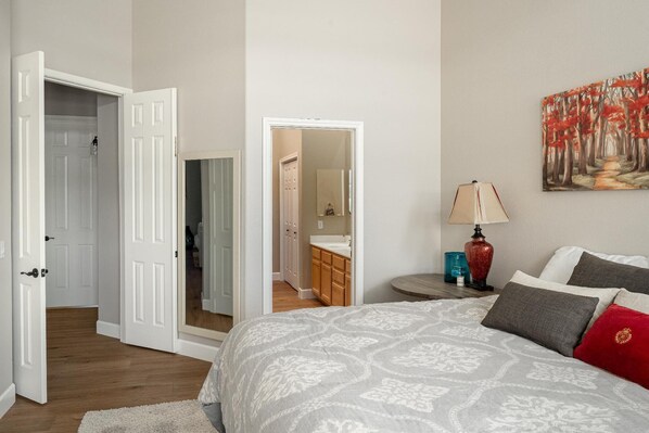 Un dormitorio con cama, mesita de noche, lámpara y un cuadro en la pared.