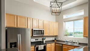 A modern kitchen with wooden cabinets, stainless steel appliances, a large window, and a chandelier. - Walk to TPC | Pinnacle Peak Views | Gated Retreat (Scottsdale)