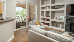A living room with a sofa, a fireplace, and a bookshelf. - Walk to TPC | Pinnacle Peak Views | Gated Retreat (Scottsdale)