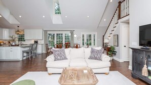 A spacious living room with a white sofa, a coffee table, and a dining area with a chandelier. - Solon Serenity: A Beautiful, Serene Setting with Mtn Views, Weekly and Monthly Discounts! (Mount Solon)
