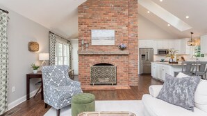 A spacious living room with a fireplace, a dining area, and a kitchen with white cabinetry. - Solon Serenity: A Beautiful, Serene Setting with Mtn Views, Weekly and Monthly Discounts! (Mount Solon)