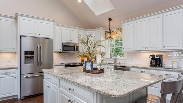 A modern kitchen with white cabinetry, stainless steel appliances, a granite countertop, and a central island with decorative items. - Solon Serenity: A Beautiful, Serene Setting with Mtn Views, Weekly and Monthly Discounts! (Mount Solon)