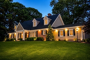 A two-story house with a well-maintained lawn, a brick chimney, and multiple windows.