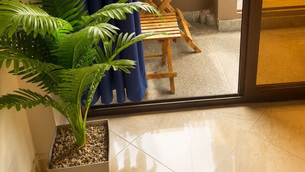Varanda com mesa de madeira, planta em vaso e vista para o verde.