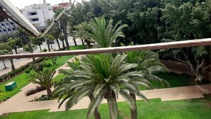 Uma varanda com vista para um jardim bem cuidado, com palmeiras e um caminho.