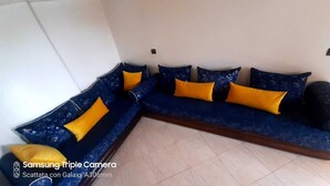 Um sofá modular com almofadas azuis e amarelas em um quarto com piso em mosaico.