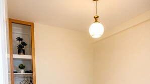 Quarto com cama, cabeceira de madeira, prateleira com plantas e luminária.