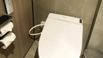 Un baño moderno con inodoro blanco, secamanos y cubo de basura.