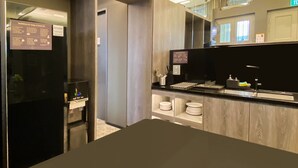 A modern kitchen with a black refrigerator, a built-in oven, and a sink with a faucet. There are cabinets and a countertop with a small dish rack. - ST Signature Jalan Besar, SHORT OVERNIGHT, 13 hours: 6PM-7AM (Singapore)