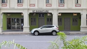 A building with a sign reading "ST SIGNATURE" and a silver car parked in front.