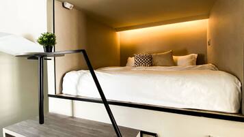 A compact room with a bunk bed, a small desk, and a potted plant.
