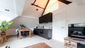 Ein modernes Loft mit Essbereich, Küchenzeile und großem Fernseher.