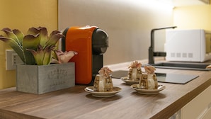 Un plan de travail de cuisine avec une machine à café, un four à micro-ondes et un pot contenant des plantes succulentes.