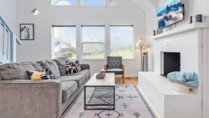 A spacious living room with a grey sofa, a wooden coffee table, and a fireplace. - Ocean Shores cozy chalet located within steps from the beach (Ocean Shores)