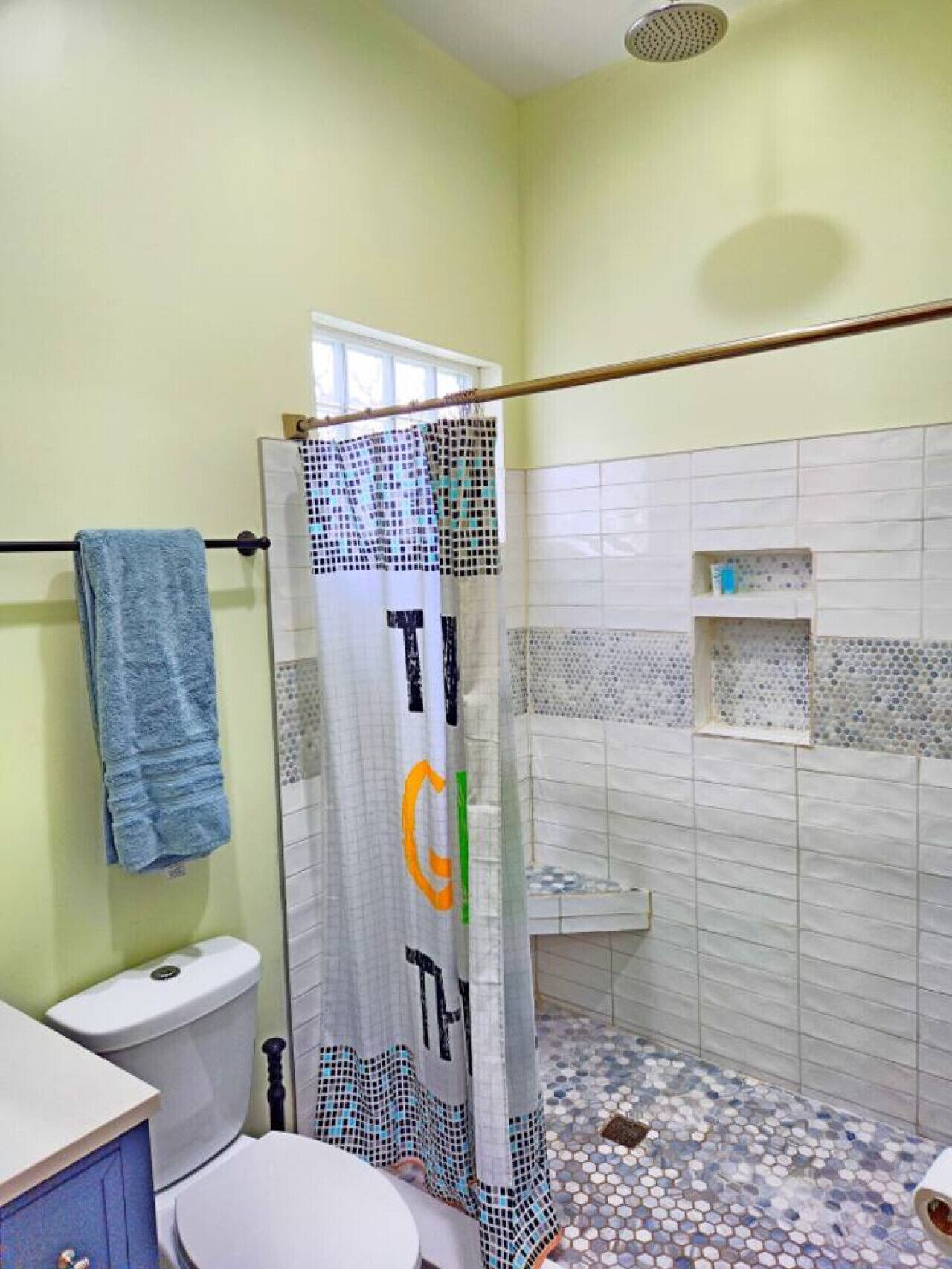 A bathroom with a toilet, a shower curtain, and a tiled floor.