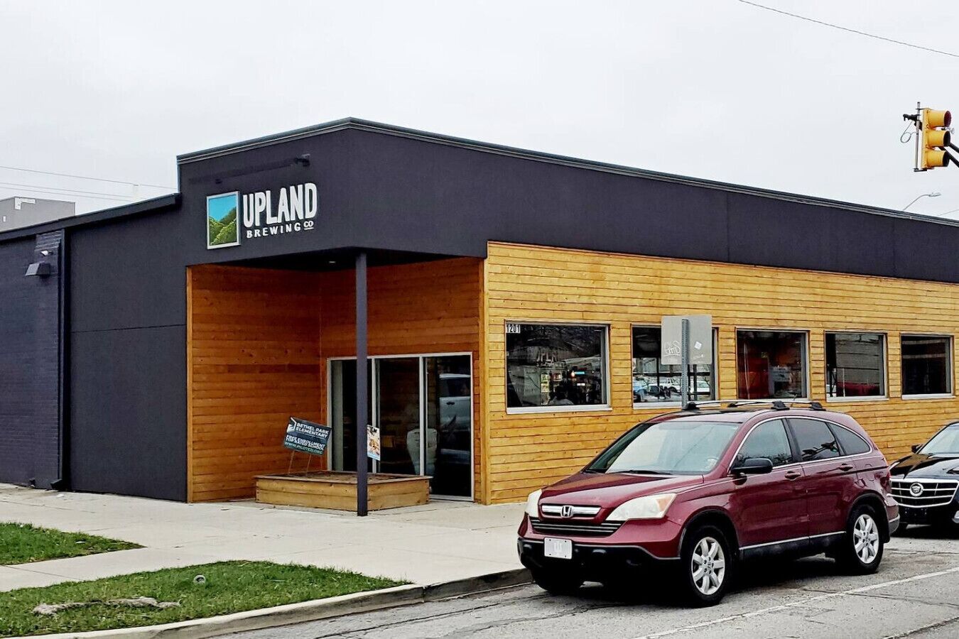 Edificio de Upland Brewing Co. con diseño moderno, destacándose por su fachada oscura y detalles de madera.