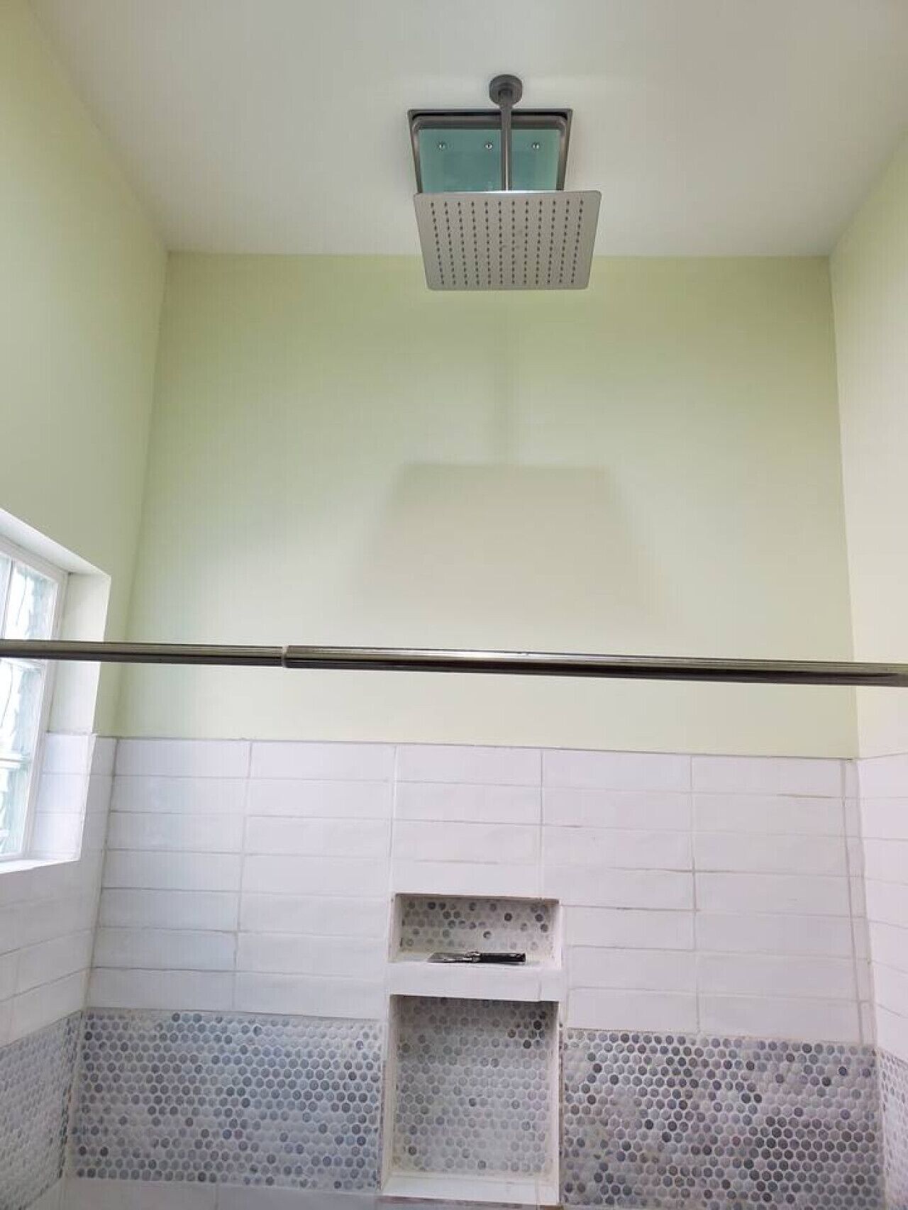 Une salle de bain avec une douche, une fenêtre et un mur carrelé.