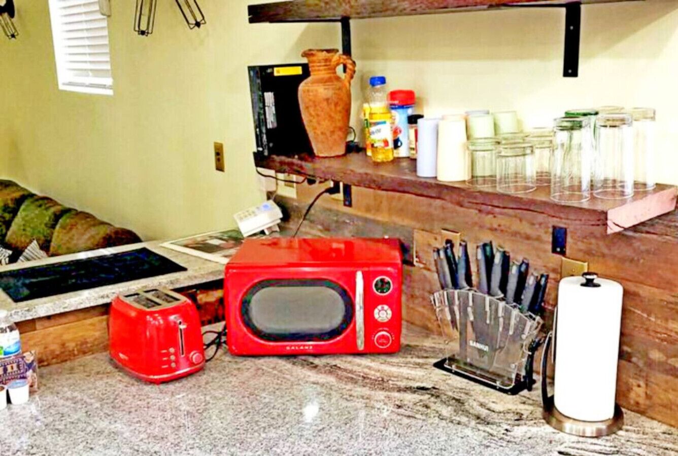 A kitchen with a red microwave, a toaster, and a knife holder on the counter.