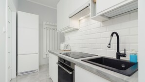 A modern kitchen with white cabinetry, a black sink, and a built-in oven.