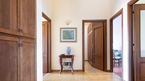 Un pasillo con puertas de madera, piso de baldosas y un cuadro en la pared.