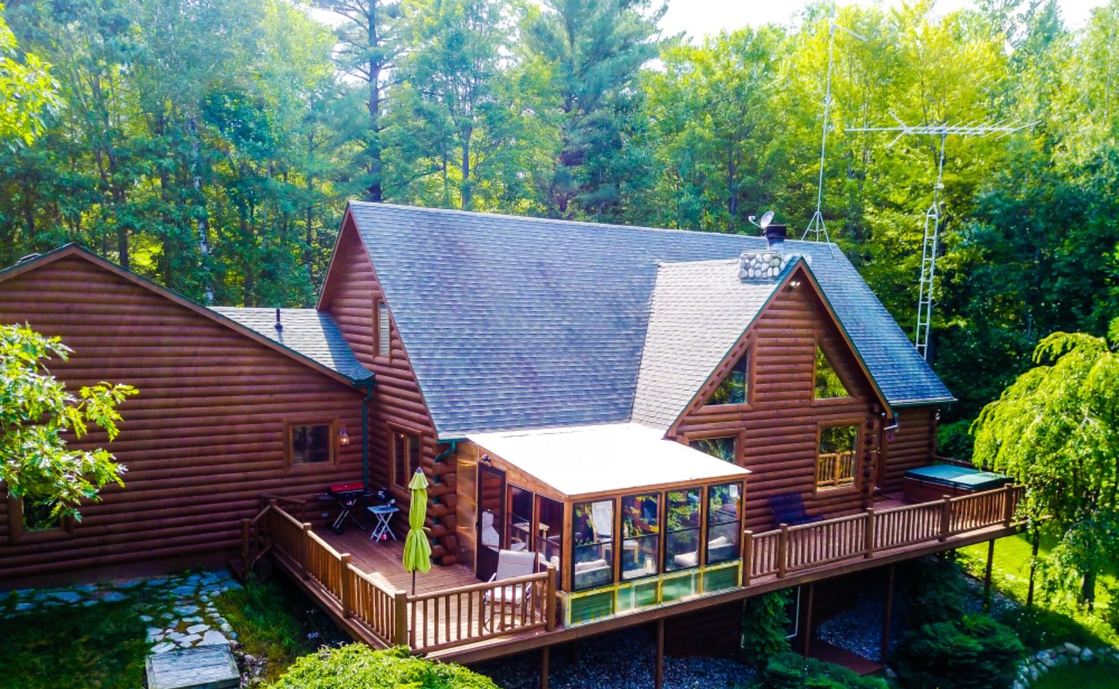 A log cabin with a deck and a glass-enclosed porch.