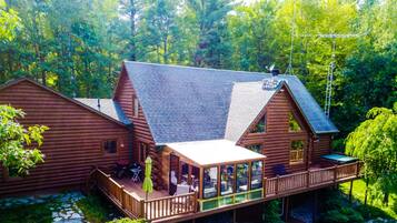 A log cabin with a deck and a glass-enclosed porch.