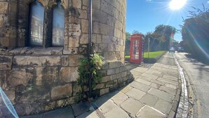 A stone building with arched windows and a red telephone booth. - Aspire Apartments (York)